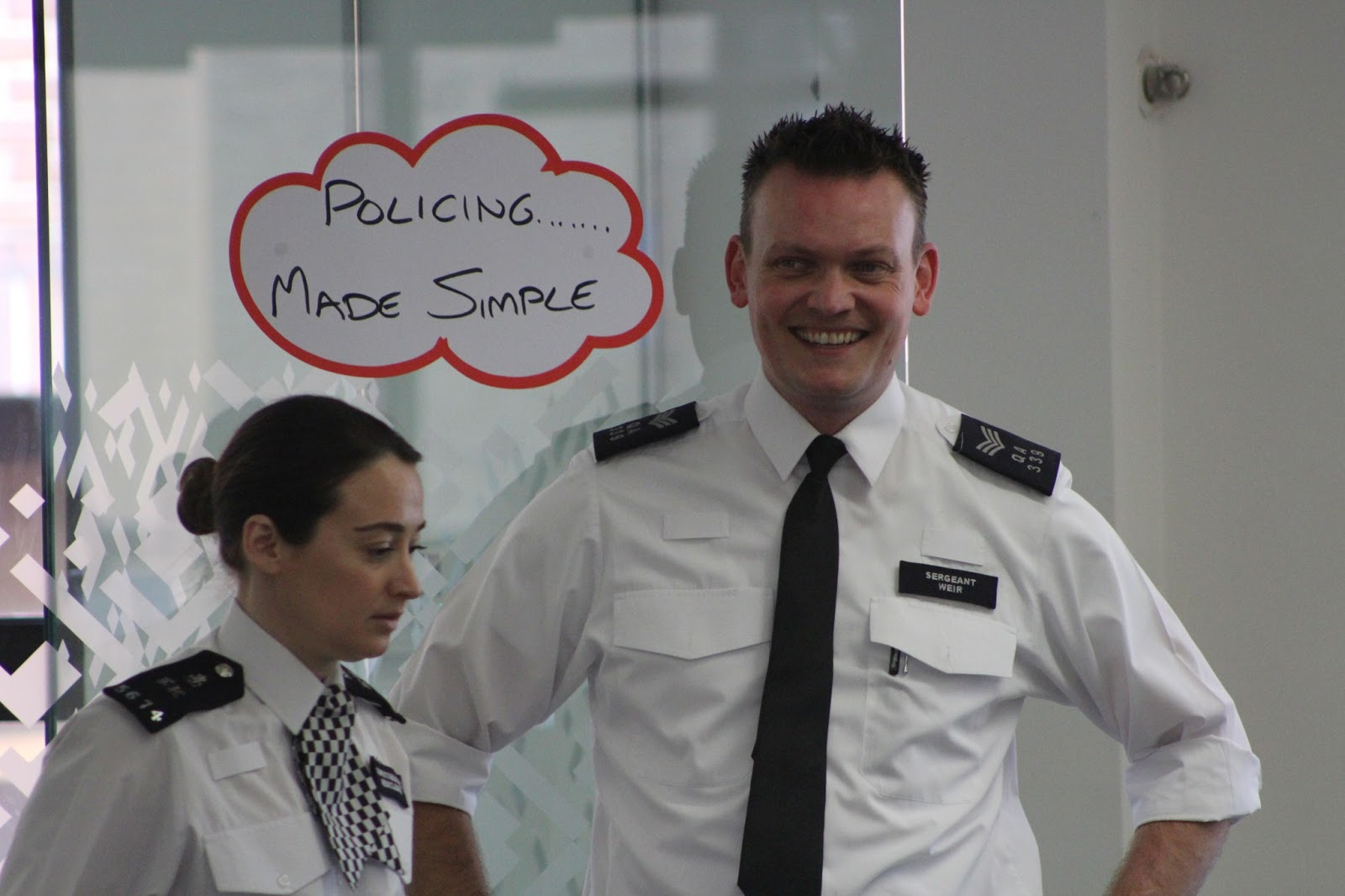 Colleagues Sgt Weir and Special Constable Neocleous\ntake a moment to reflect in front of a sign that reads: Policng made simple